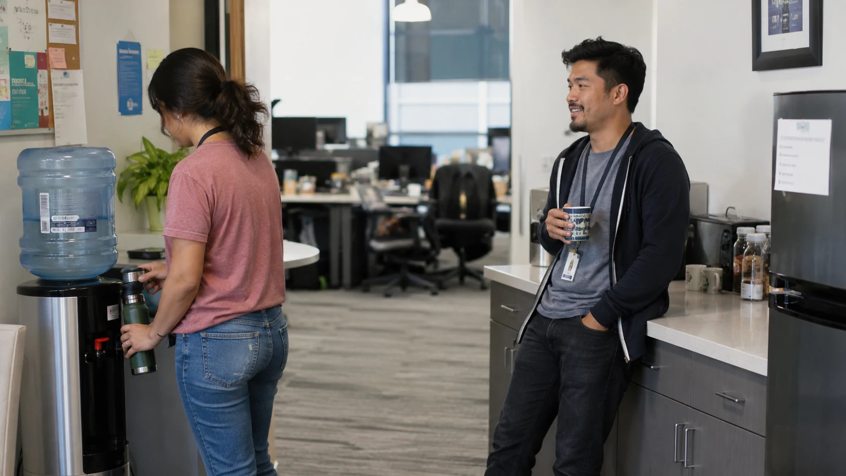 two coworkers talking near a water cooler in a break room