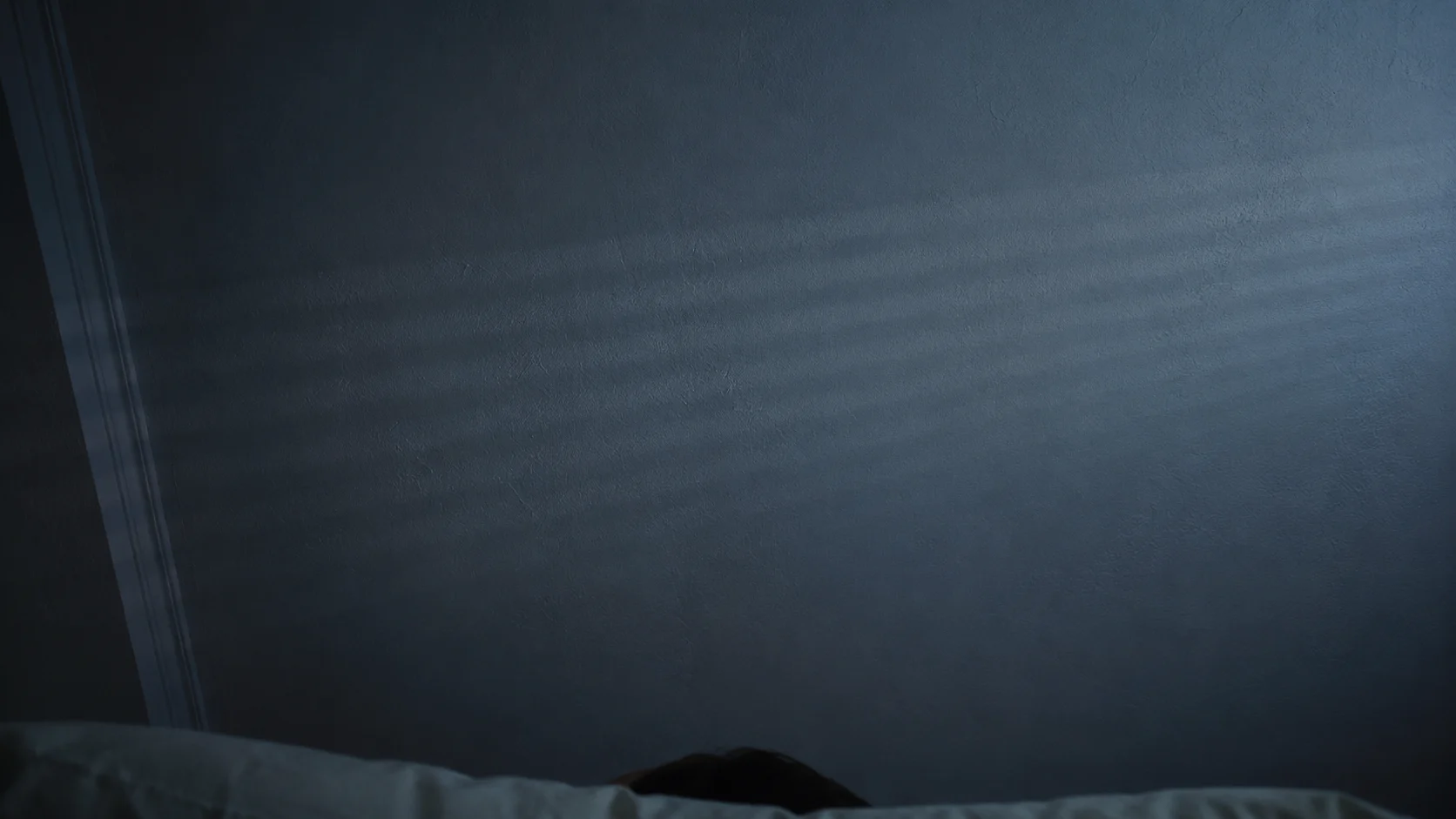 ceiling viewed from a bed at night, streetlight through blinds