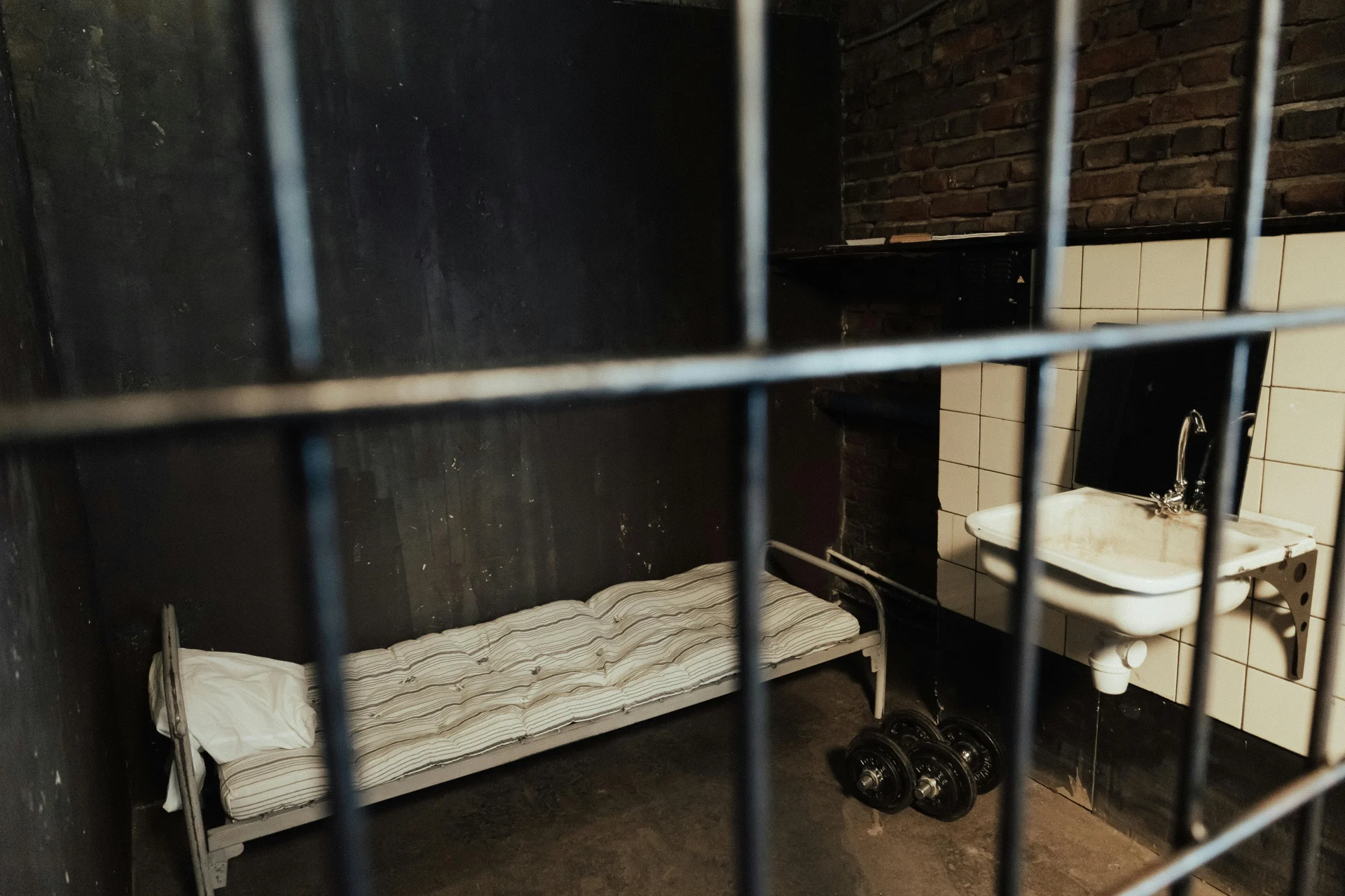 Solitary figure in a prison-like room with waves crashing on a cliff outside, symbolizing resilience and inner strength.