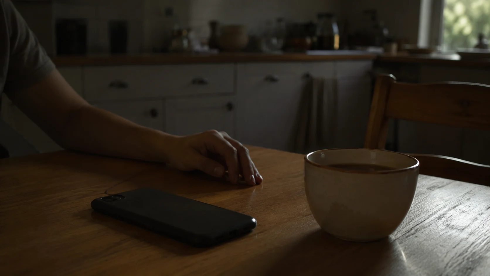 phone face-down on table next to cooling cup of tea