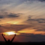 Featured image for gratitude quotes showing open arm appreciating a sunset